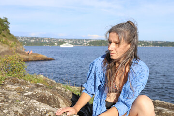 Woman on stone beach. Woman by the fjord in Norway, Oslo.