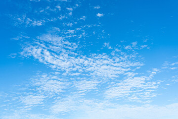 Obraz premium A serene blue sky with snowflakes, featuring clouds and a hint of the sea in a bright, clear day