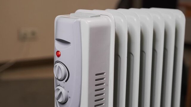 A housewife turns on an electric heater in cold weather.