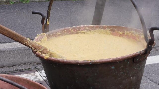 A large cooper pot of corn porridge is boiling