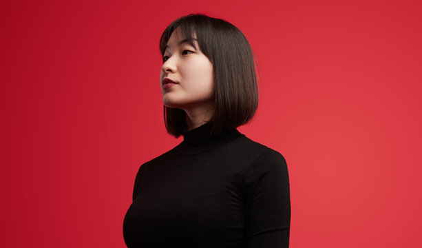 Side profile of a confident woman in a black turtleneck, standing against a bold red background. The image radiates confidence and elegance.