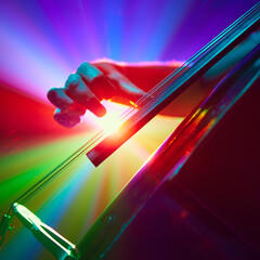 Close up of musician playing double bass elegantly plucking strings with his fingers in neon light. Instrumental solo. Concept of classical and modern music, entertainment, jazz. Ad © master1305