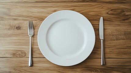 A minimalist dining setup featuring a white plate, fork, and knife on a wooden table, perfect for culinary presentations.