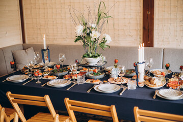 A festive and beautifully decorated wedding table. Decorated with flowers.various bottles of drinks, beautiful dishes, salads and sliced meat rolls.vegetable slicing.