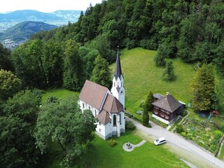 Aerial view of Kuratienkirche Meschach surrounded by lush greenery. Gotzis, Austria