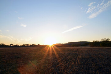 Sunrise on sunset in summer, sun rays over horizon with beautiful sky and landscape background