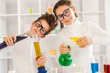 Two children wearing glasses conducting a science experiment in a classroom laboratory setting. Educational and fun learning environment.