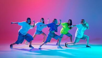 Five kids strike dynamic hip hop poses with intense focus and style against gradient pink purple background in neon light. Concept of modern dance styles, youth culture, active lifestyle