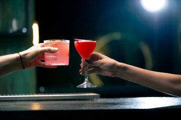 Close up of two people cheering cocktails in bar or disco club drinks and cocktails concept