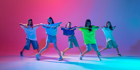 Children perform a high-energy hip hop dance, showing skills of synchronization against gradient...