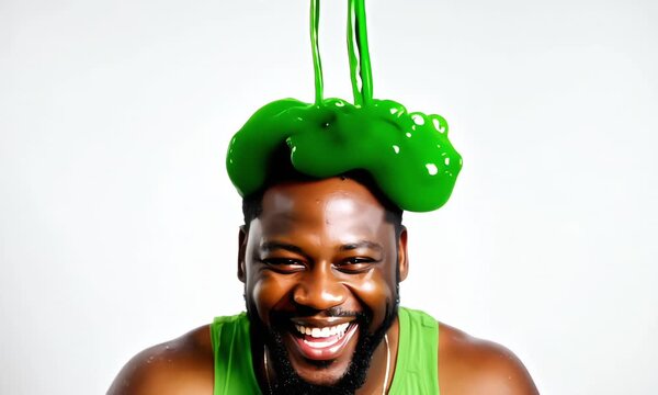 Smiling man with bright green liquid slime on his head on white background 