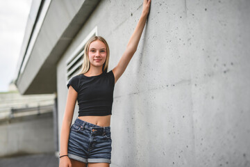 young girl standing at city street. Outside portrait of joyful beautiful teen over urban background.