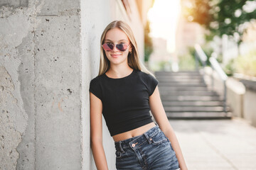 young girl standing at city street. Outside portrait of joyful beautiful teen over urban background.