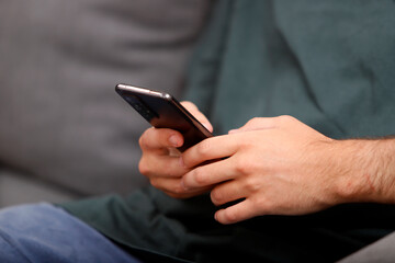 young man's hands holding a cell phone