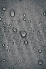 Extreme close up photograph of water droplets on a textured fabric. Vertical.