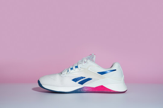 Strasbourg, France - August 2024 : Reebok Nano X4 new training shoes on pink and white background from the side. Stylish monochrome shoes for active people that incorporate new health technology