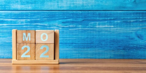 Vibrant blue background showcases a wooden color calendar with May 22nd highlighted, surrounded by empty space, evoking a sense of springtime freedom and new opportunities.