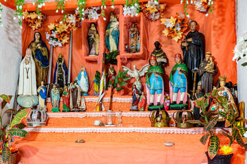 Colorful altar with several Catholic saints decorated with plants and fabrics