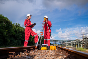 Fototapeta premium Surveyor engineers team wearing safety uniform and blueprint checking inspection by theodolite telescope to measurement level position railway construction site is industry transportation concept.