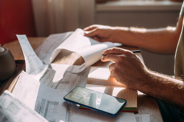 Close-up of men's hands with a calculator and utility bills. The concept of rising prices for...