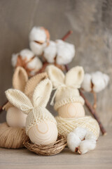 Wooden Easter eggs in crochet knitted hats with rabbit ears in nest. Easter celebration concept