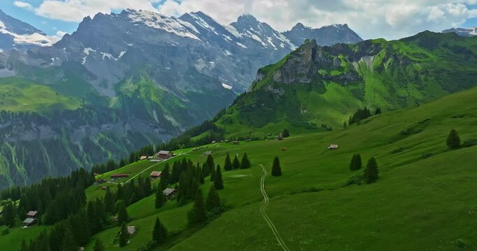 Aerial view of the small village of Gimmelwald. Swiss mountain village with traditional houses against snowy mountains. Green alpine valley in Switzerland. Alps in summer morning