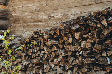 Chopped firewood pile stacked under the roof. Woodpile board wall. Wood. Old dry wooden pine heap. Brown textured background. Natural resources. Solid fuel. Winter preparation concept. Rustic style
