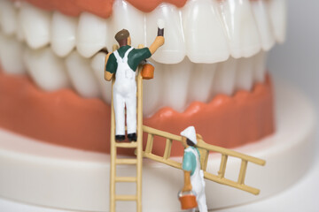 Painter painting teeth white, care work miniature figures scene, close up
