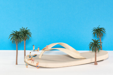 Vacationers relaxing on a flip flop sandal on an oasis, miniature figures scene