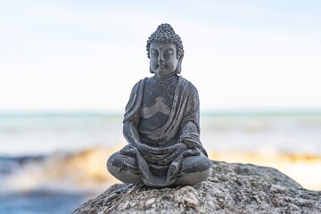 Kleine Buddha Statue auf Felsen am Meer, Meditation am Kraftort