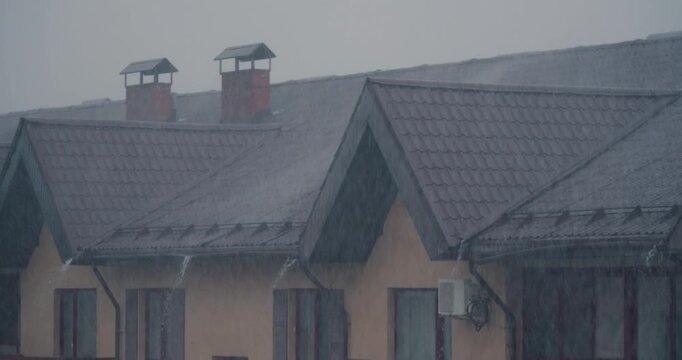 A small suburban condominium during heavy rain. The tiled roof of the house and endless streams of water from the sky. 60 fps 4k footage.