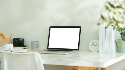 Minimalist workspace with a laptop placed in the center of a white desk.