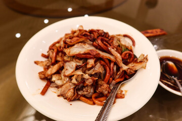 close up of Chinese Shanghai style stir fried pork beef vegetables noodles with soy sauce on a white plate