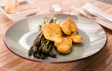 Fried chicken breast pieces with asparagus on plate