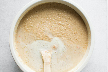 Overhead of moi moi mixture in a white ceramic bowl, top view of nigerian bean pudding being mixed, process of making nigerian moi moi