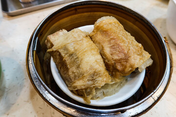 close up of Chinese Cantonese Dim Sum Steamed Chicken bean curd skin Roll with shrimp fish skin in a bamboo steamer container ordered in 