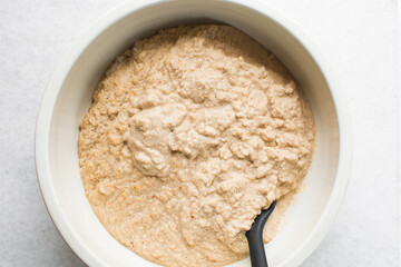 Overhead of moi moi mixture in a white ceramic bowl, top view of nigerian bean pudding being mixed, process of making nigerian moi moi