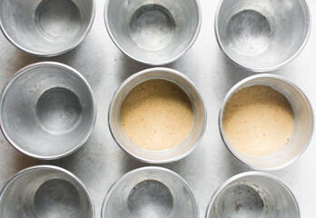 Overhead of moi moi mixture in silver pans, top view of nigerian bean pudding about to be steamed in steel pans, process of making nigerian moi moi
