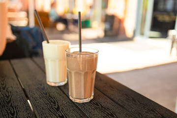 Two pink fruit milk cocktails in glasses with black tubes spiral pattern for milkshakes, cocktails, juices stand on table in street cafe. Bokeh background, backdrop, High quality photo