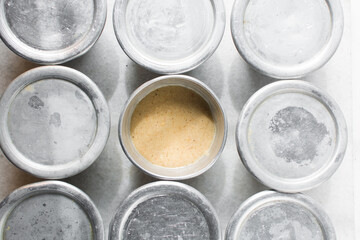 Overhead of moi moi mixture in silver pans, top view of nigerian bean pudding about to be steamed in steel pans, process of making nigerian moi moi