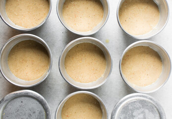 Overhead of moi moi mixture in silver pans, top view of nigerian bean pudding about to be steamed in steel pans, process of making nigerian moi moi