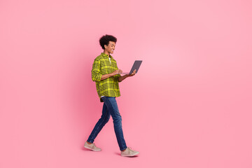 Full length portrait of nice young man walk use laptop wear shirt isolated on pink color background