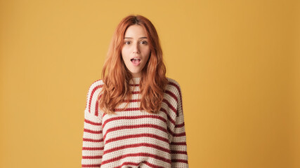 Obraz premium Very surprised girl looking at camera in studio on yellow background