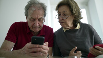 Elderly couple focused on smartphones, seated together, engaged in modern technology, exploring...