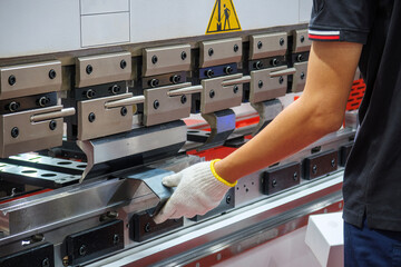 Close up the press brake bending machine operator hold the sheet metal parts with safety glove.