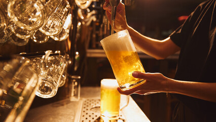 Female bartender pouring lager foamy beer from tap into glass. Organic drinks. Concept of beer, brewery, pub, Oktoberfest, traditions