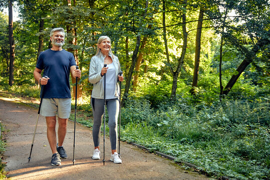 Active and Engaged Seniors Delight in a Nature Walk in the Park Using Nordic Poles - Powered by Adobe