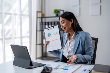 A woman is sitting at a desk with a laptop and a piece of paper