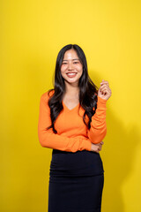 A woman in an orange shirt and black skirt is smiling and posing for a photo