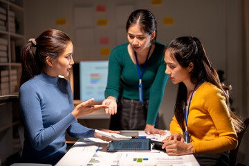 Three women are sitting at a table, discussing something